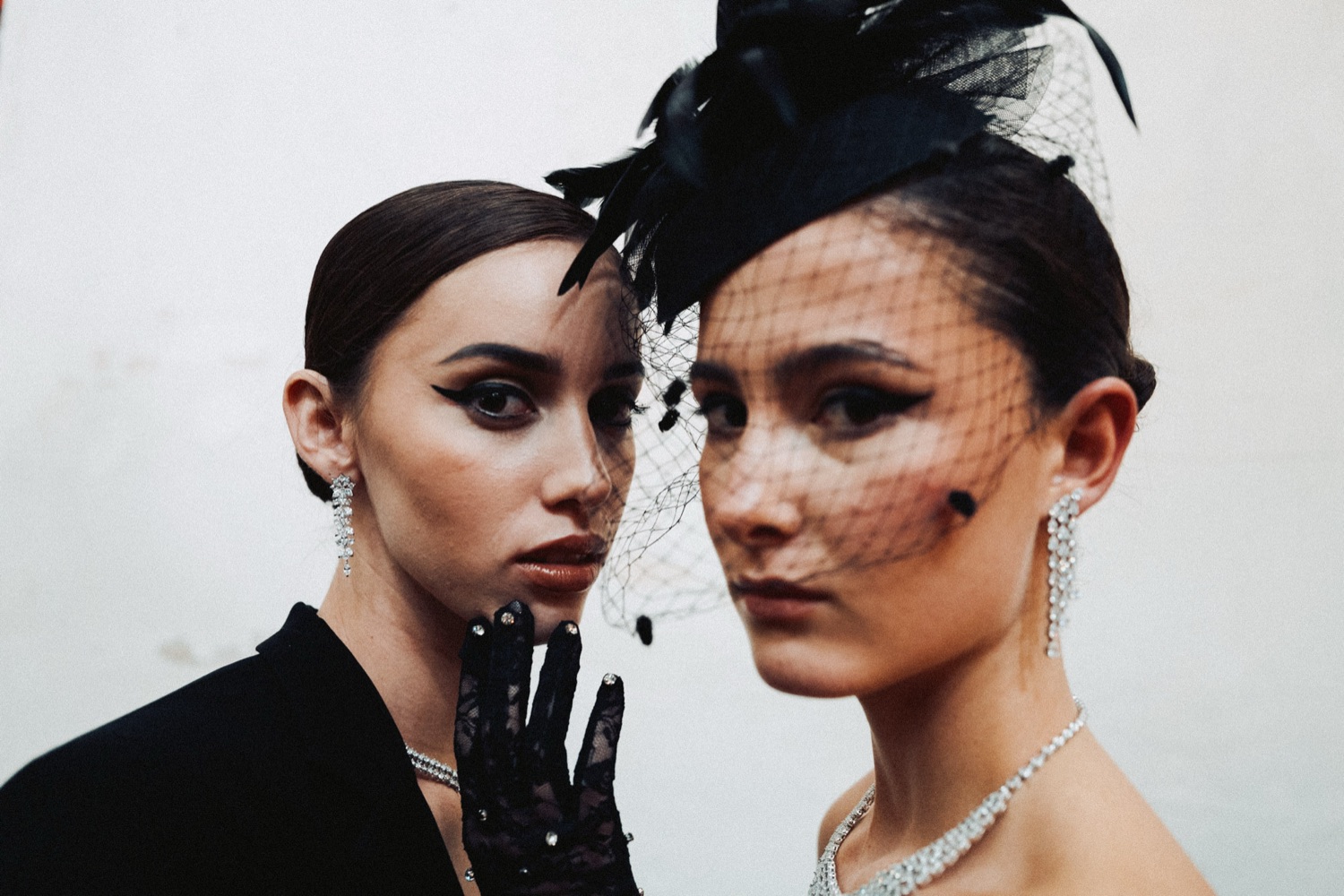 Two models in black veils and feathered headpieces, editorial portrait