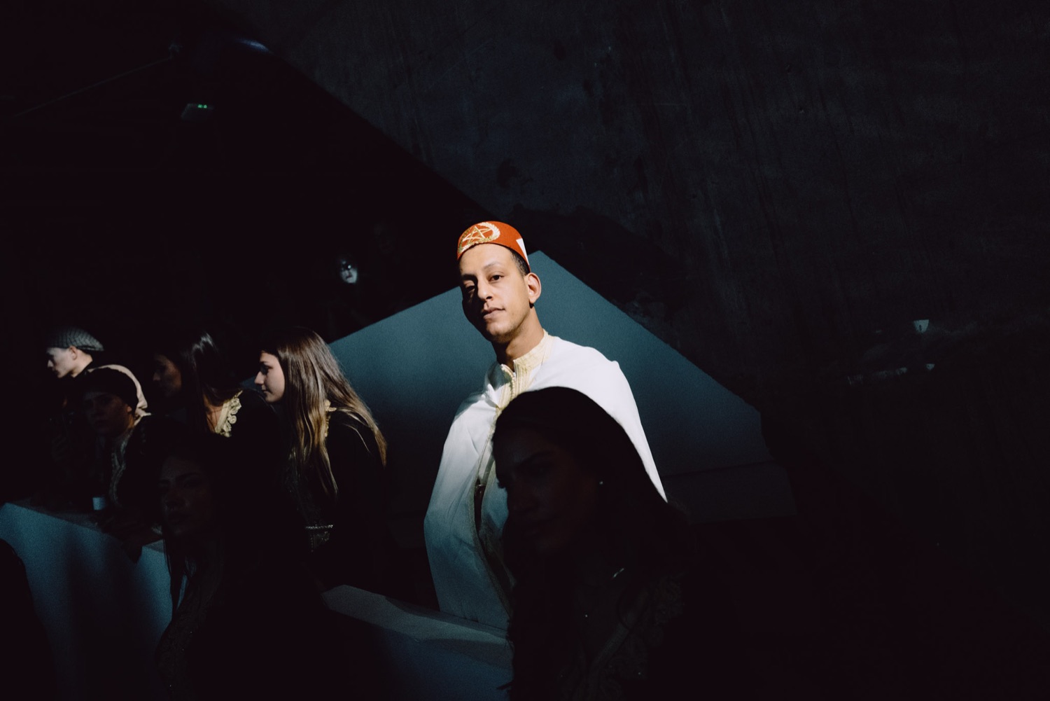 Moody show portrait, sitter in an orange cap under low light