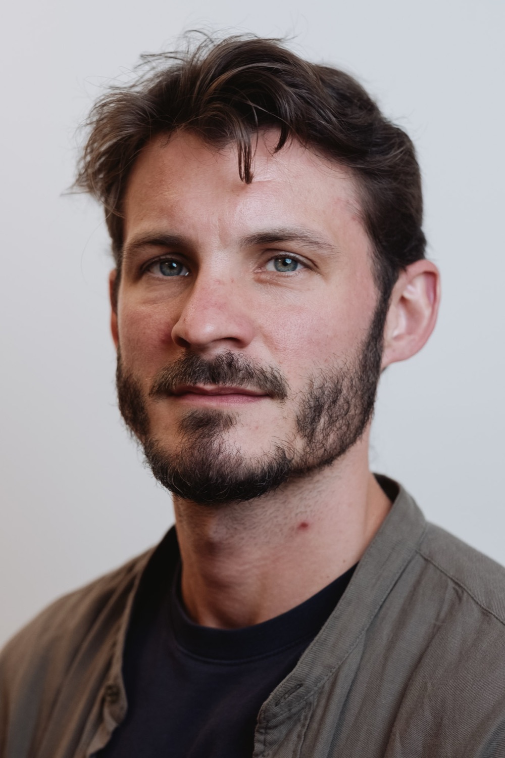 Relaxed professional headshot of a bearded man in an olive jacket