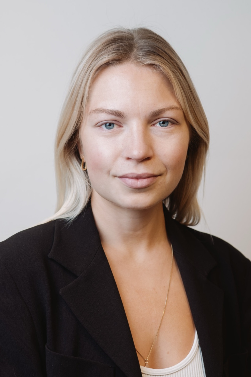 Professional headshot of a blonde woman in a dark blazer