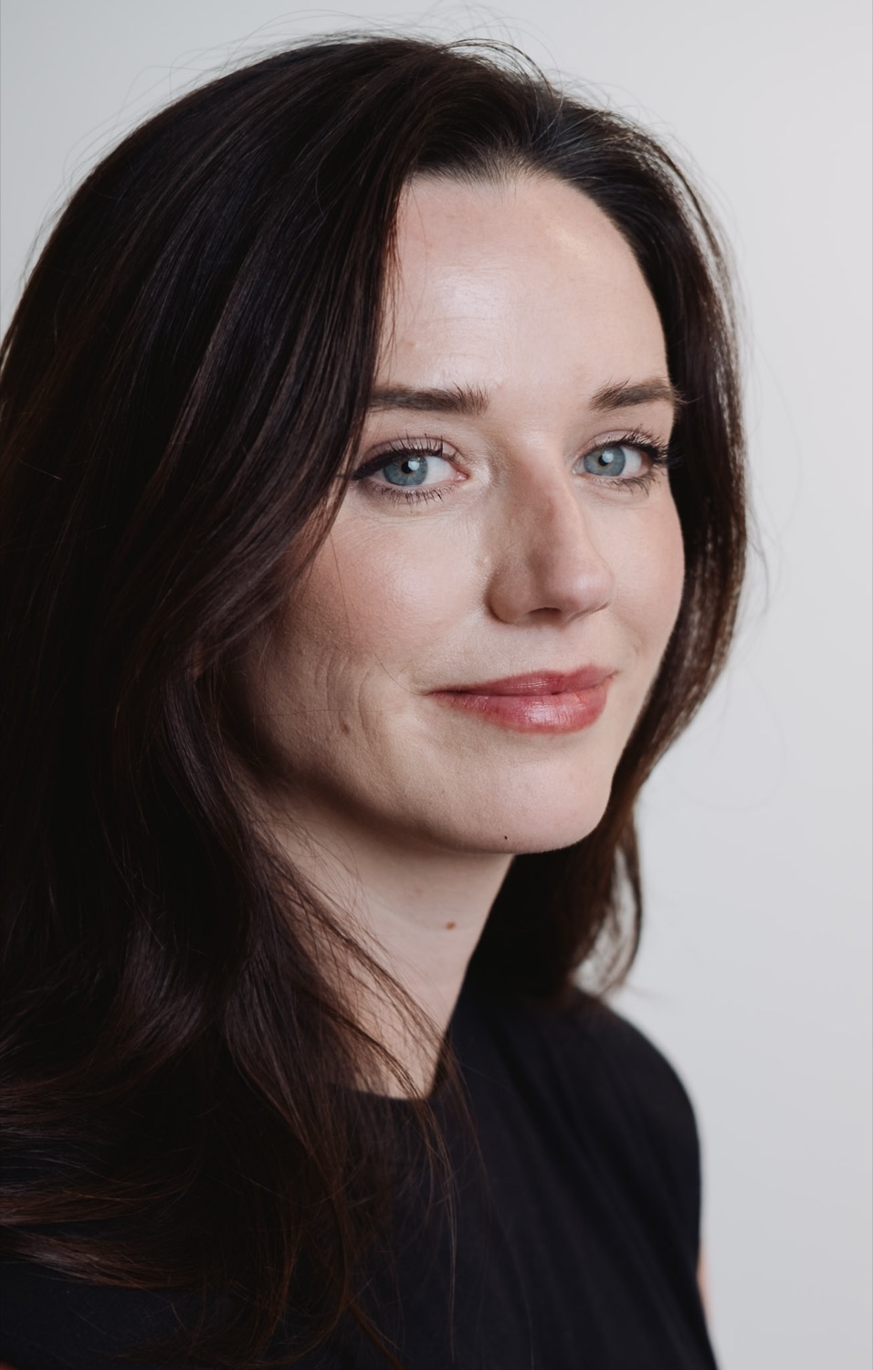 Professional headshot of a dark-haired woman against a neutral backdrop