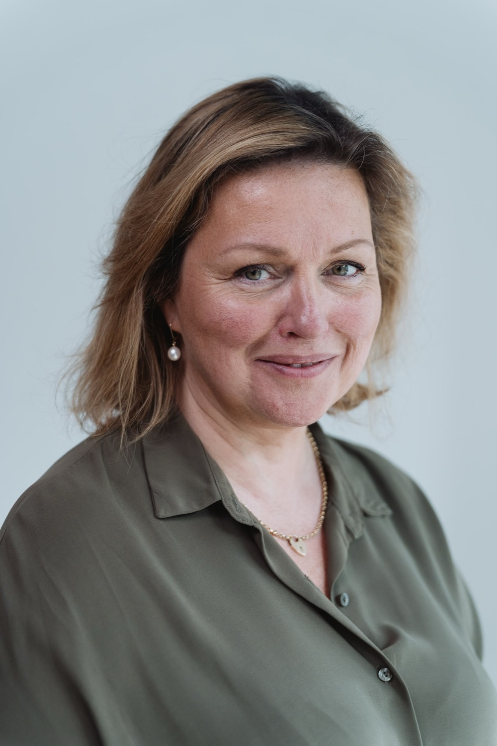 Natural-light professional headshot of a blonde woman in an olive blouse