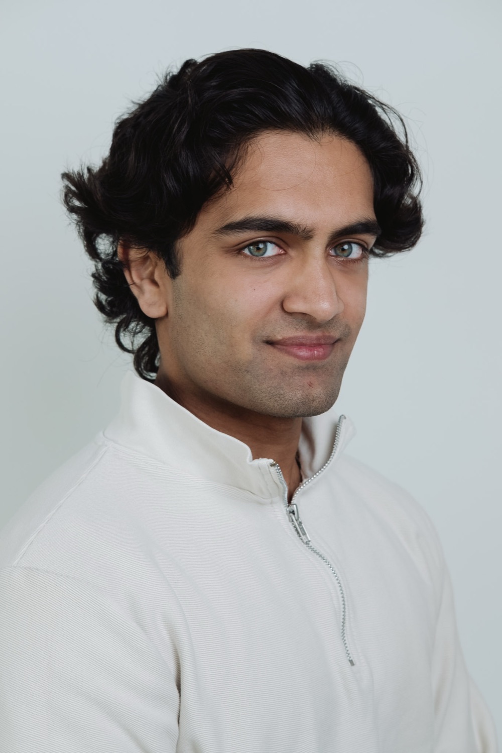 Professional headshot of a young man in a white polo shirt