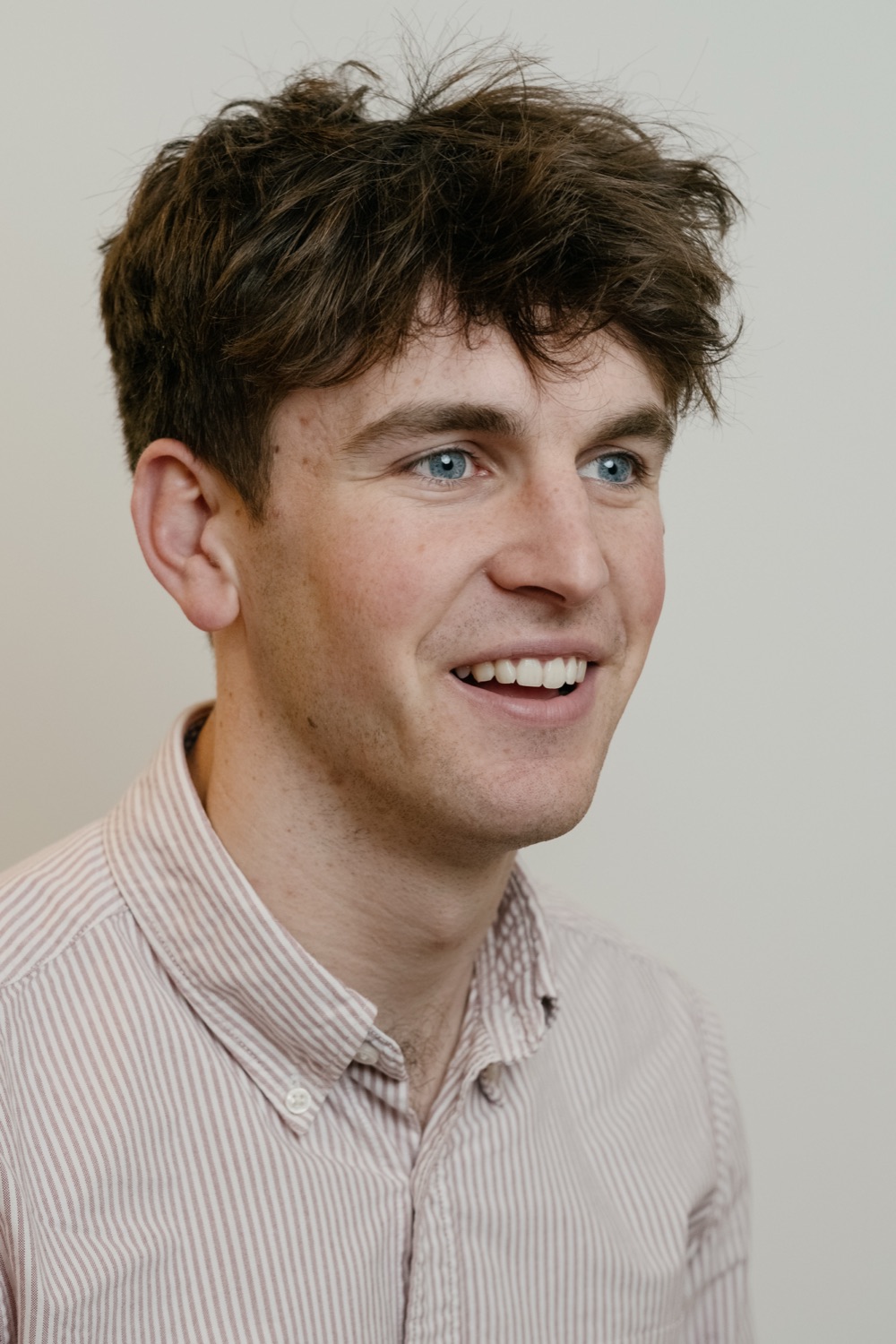 Smiling professional headshot of a young man in a striped shirt
