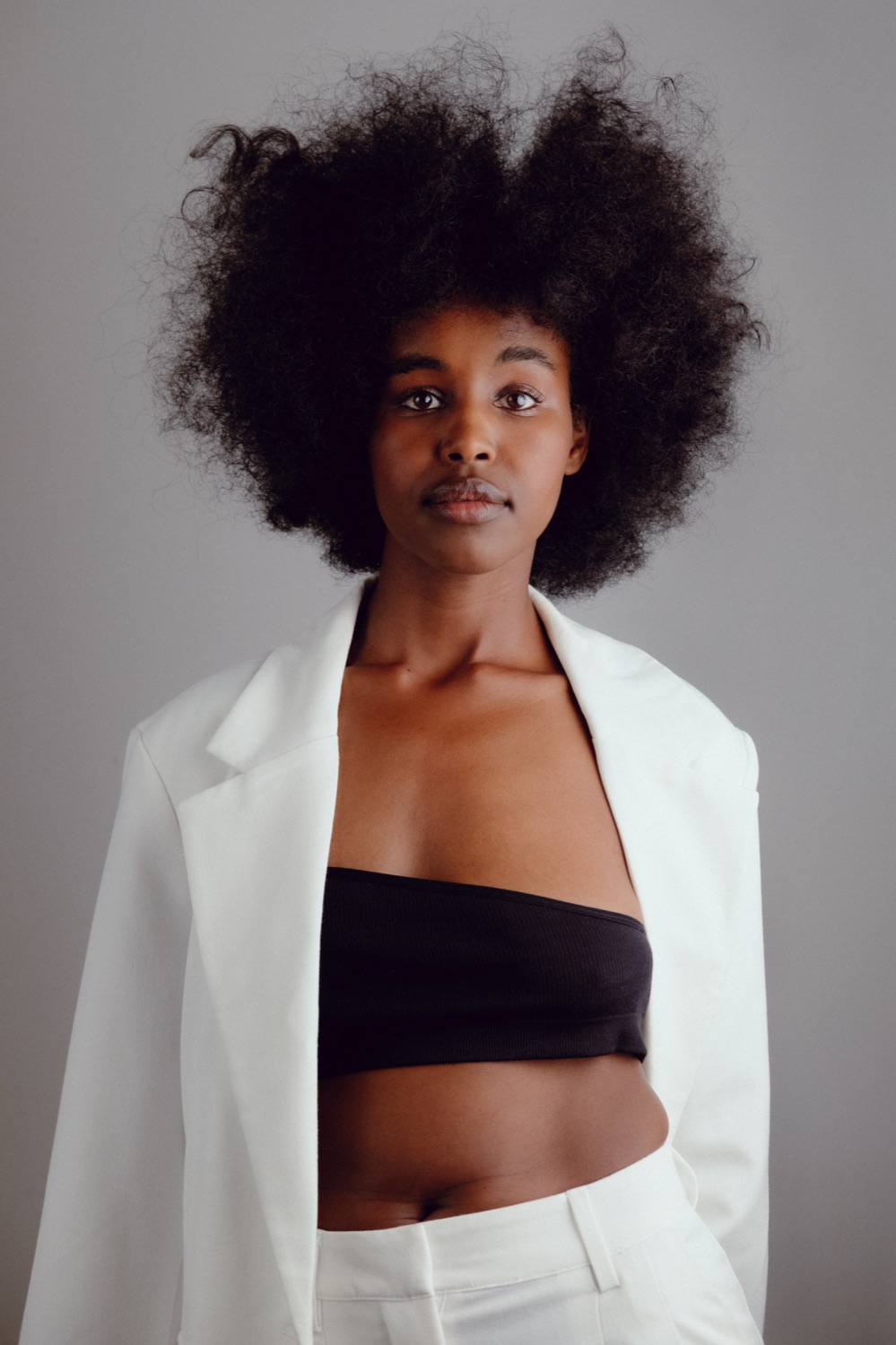 Studio portrait of a model in a white suit against a grey backdrop