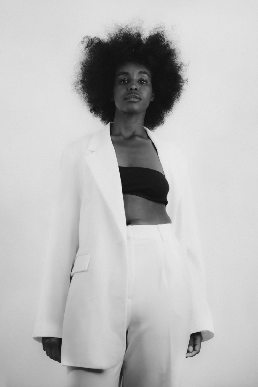 Full-length studio portrait of a model in a white tailored suit