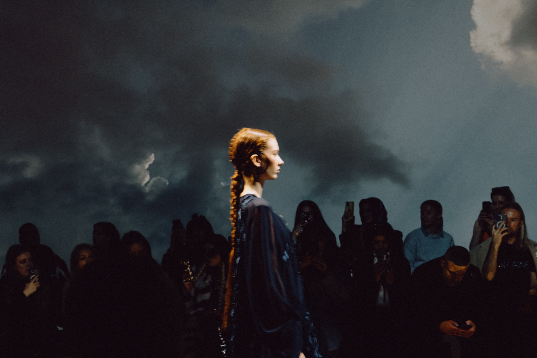 Runway model lit against a projected stormy sky